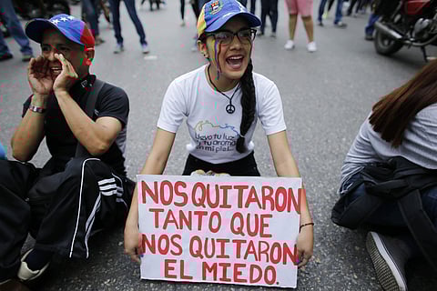 A woman holds up a sign with a message in Spanish that reads: 'They took away so much, that they took away our fear' in the middle of a road during a protest against President Nicolas Maduro. AP