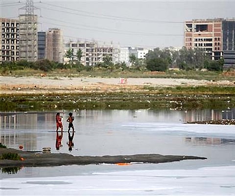 People walk through the polluted waters of the Yamuna River. (AP)