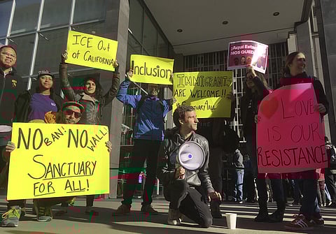 Protesters hold up signs outside a courthouse where a federal judge will hear arguments in the first lawsuit challenging President Donald Trump's executive order to withhold funding from communities that limit cooperation with immigration authorities Frid