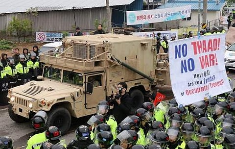 Protesters and police stand by as trailers carrying US THAAD missile defence equipment enter a deployment site in Seongju, early on April 26, 2017. | AFP
