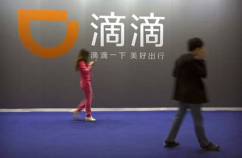 Visitors walk past a sign for Chinese ride-hailing service Didi Chuxing at the Global Mobile Internet Conference (GMIC) in Beijing | AP