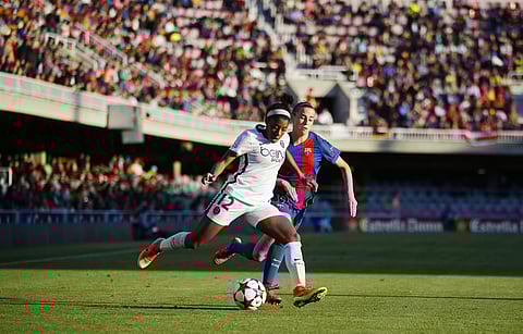 PSG's Ashley Lawrence, left, duels for the ball against FC Barcelona's Barbara Latorre during the Women's Champions League semifinal first leg soccer match between FC Barcelona and Paris Saint Germain, at the Miniestadi stadium in Barcelona, Spain, Saturd