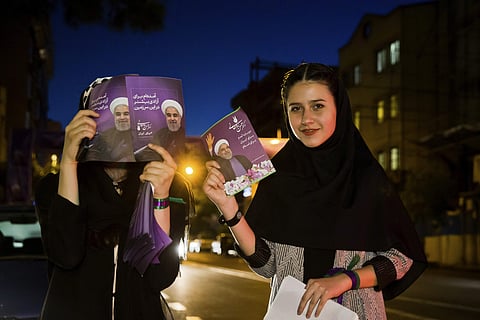 In this Wednesday, May 10, 2017 photo, supporters of Iranian President Hassan Rouhani hold his posters for May 19 presidential election in downtown Tehran, Iran. (AP)