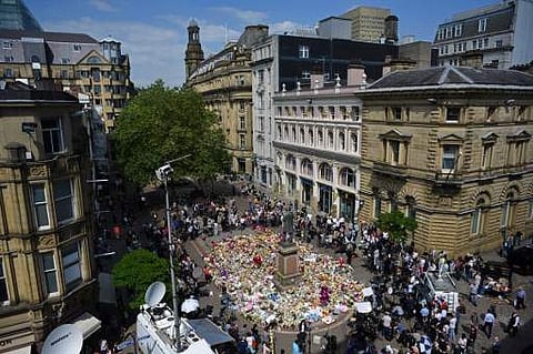 People gather to see flowers and messages of support left around a statue of Richard Cobden in St Ann's Square in Manchester, northwest England on May 25, 2017.