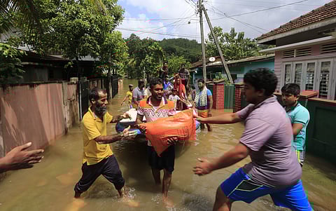 Flood victims carry relief materials at Wehangalla village in Kalutara district, Sri Lanka. (Photo | AP)