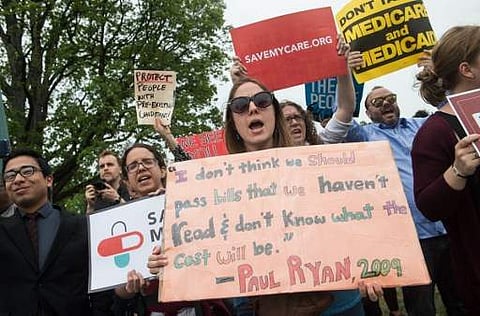 Protesters hold signs and shout at lawmakers walking out of the US Capitol on May 4 after the House of Representatives narrowly passed a Republican effort to repeal and replace Obamacare. (File Photo | AFP)