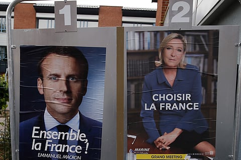 Election campaign posters for French centrist presidential candidate Emmanuel Macron and far-right candidate Marine Le Pen are displayed in front of a polling station. (Photo | AP)