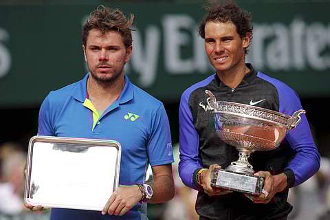 Spain's Rafael Nadal right holds the trophy as he celebrates winning his tenth French Open title against Switzerland's Stan Wawrinka left in three sets 6-2 6-3 6-1 during their men's final match of the French Open tennis tournament at the Roland Garros st