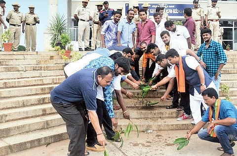 BJP members sprinkle ‘gomutra’ to ‘purify’ Kalamandira where beef was served at a function, in Mysuru on Monday | Udayashankar S