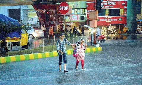 Two college-goers, all drenched, cross a waterlogged road near RTC Complex in Visakhapatnam on Wednesday | Express