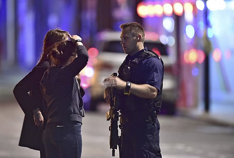 An armed Policeman talks to members of the public outside London Bridge Hospital as police are dealing with an incident on London Bridge in London, Saturday, June 3, 2017. Witnesses reported a vehicle hitting pedestrians and injured people on the ground.(