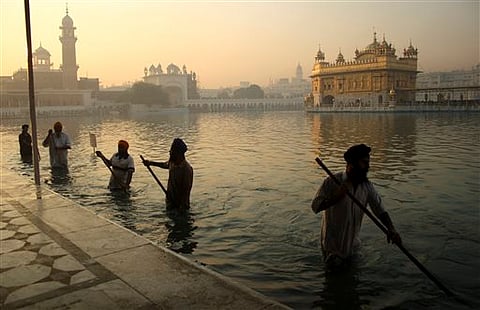 Indian Sikh devotees clean the tank early in the morning at the Golden Temple. |AP