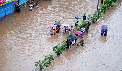 People make their way through a flooded street after heavy rainfall in Assam. | PTI