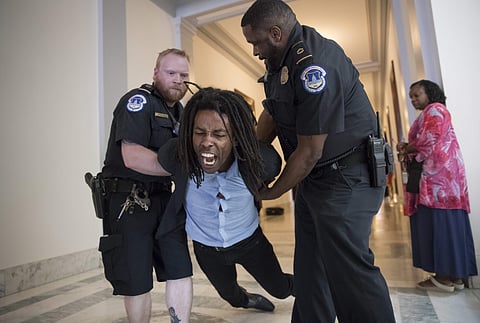 A demonstrator is taken into custody by U.S. Capitol Police as activists protest against the Republican health care bill outside the offices of Sen. Jeff Flake, R-Ariz., and Sen. Ted Cruz, R-Texas, Monday, July 10, 2017, on Capitol Hill in Washington. (AP