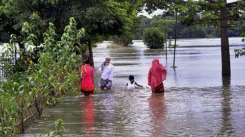 Villagers wading through a flooded street at Kureni Bori in Morigaon district of Assam.