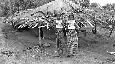 Puna Mukhi and his wife Malati display Aadhaar cards in front of their hut | Express