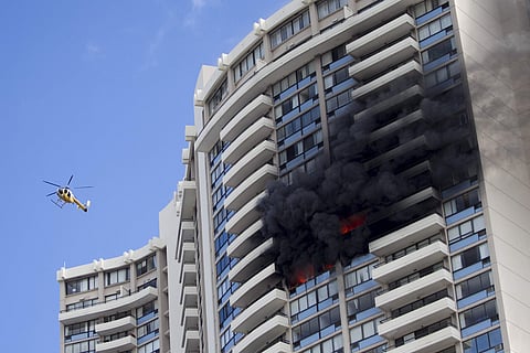 A Honolulu Fire Department helicopter flies near a fire burning on a floor at the Marco Polo apartment complex, Friday, July 14, 2017, in Honolulu. (AP)