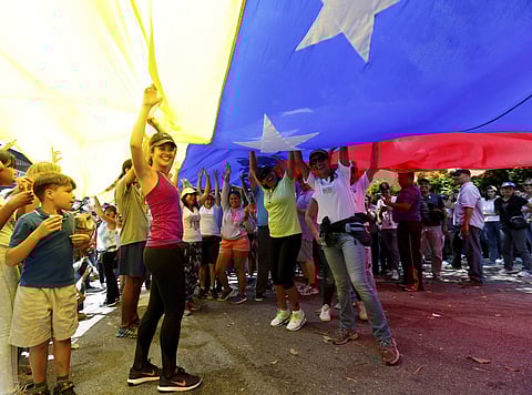 Opposition members wave a Venezuelan flag outside a poll station during a symbolic referendum in Caracas, Venezuela, Sunday, July 16, 2017. | AP