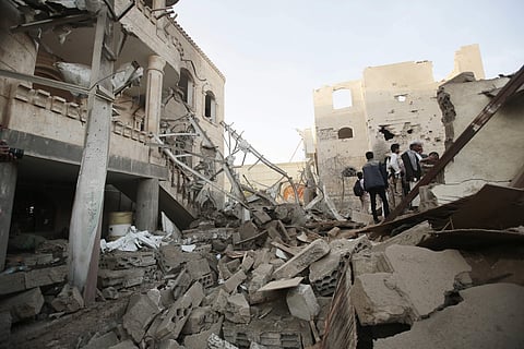 People stand on the rubble of houses destroyed by Saudi-led airstrikes in Sanaa. | AP