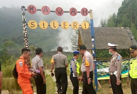 Police officers and a rescuer stand at a path leading to Sileri Crater after it erupted in Dieng, Central Java, Indonesia, Sunday, July 2, 2017. The crater at Dieng Plateau spewed cold lava, mud and ash as high as 50 meters (164 feet) into the sky when it