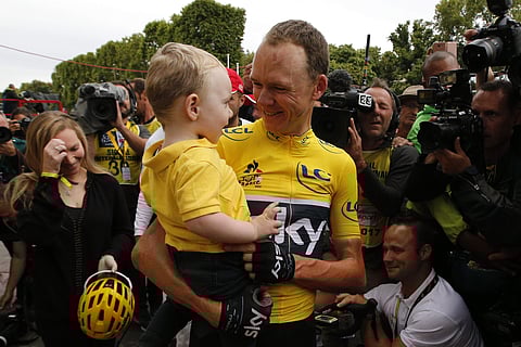 Tour de France winner Britain's Chris Froome, wearing the overall leader's yellow jersey, holds son Kellan as his wife Michelle, left, reacts the Champs Elysees avenue. | AP