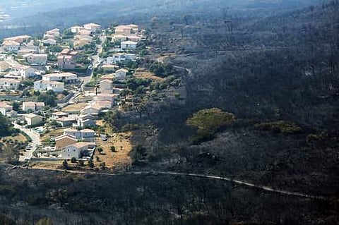 An aerial view shows houses adjacent to terrain scorched by wildfire near the village of Biguglia, Corsica island, France. Hundreds of firefighters are battling blazes fanned by high winds in more than a dozen zones in the Riviera region of southern Franc