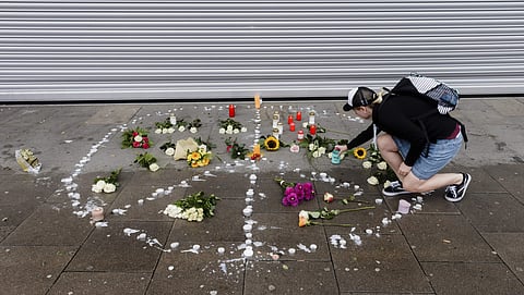 A woman places flowers near a supermarket in Hamburg (AP)