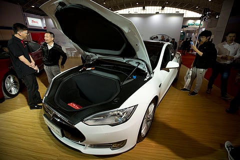Visitors gather around a Tesla Model S electric car on display at the Beijing International Automotive Exhibition in Beijing. (AP File Photo)