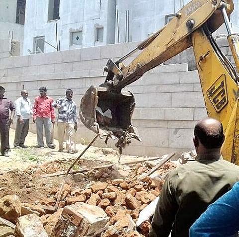 GHMC workers trying to demolish a compound wall of a house in Hyderabad on Monday| Express PHOTO
