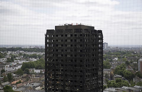 FILE - In this Friday, June 16, 2017 file photo, emergency workers walk on the roof of the fire-gutted Grenfell Tower in London, after a fire engulfed the 24-storey building. | AP