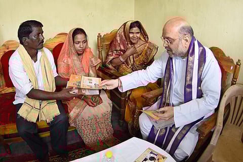 Amit Shah handing over leaflets to a family of Basantpur village, on the outskirts of Bhubaneswar, on Thursday | Express