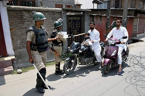 Security jawans stop motorcyclists during restrictions in down town Srinagar on Friday. | PTI