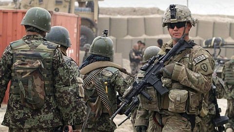 Afghan soldiers, left, walk past a U.S. Army soldier outside of a military base in Panjwai, Kandahar province south of Kabul, Afghanistan on Sunday, March 11, 2012. (Photo | AP)
