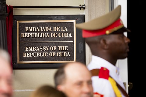 FILE - In this july 20, 2015 file photo, a member of the Cuban honor guard stands next to a new plaque at the front door of the newly reopened Cuban embassy in Washington. The State Department has expelled two diplomats from Cuba’s Embassy in Washington f