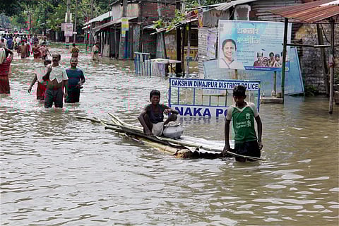 People wade through a flooded road caused due to the overflow of Atrai river at Balurghat South Dinajpur on Tuesday. | PTI