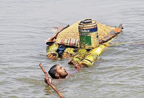 A villager pulls a makeshift banana raft loaded with much-needed foodgrains in floodwaters as he shifts from an inundated village in Araria district of Bihar on Monday | PTI