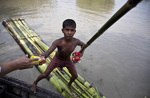 A flood affected boy on a makeshift banana raft collects biscuit packets distributed by a government official from a boat in Pokoria village, east of Guwahati, north eastern Assam state, Monday, Aug. 14, 2017. (Photo | AP)