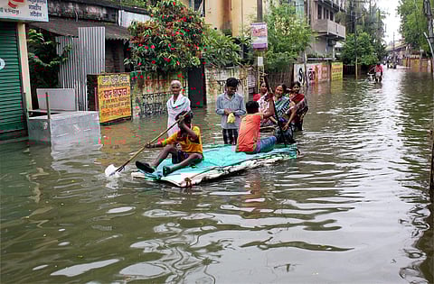 People wade through a flooded road due to overflow of Atreyee river at Balurghat in South Dinajpur district of West Bengal on Wednesday. | PTI