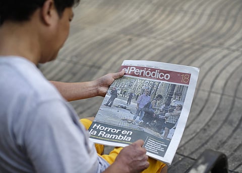 A man looks at a newspaper showing pictures of the attack in Las Ramblas, Barcelona, Spain on Friday. (Photo | AP)