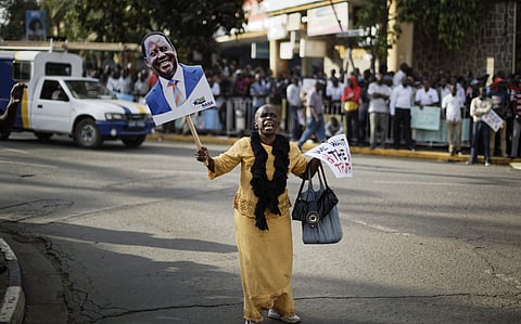 A supporter of main opposition leader Raila Odinga holds a placard of his face as she attends a small demonstration outside the Supreme Court in downtown Nairobi | AP