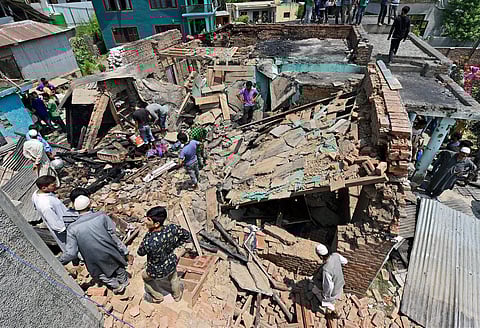 Villagers standing on the debris of a house which was destroyed during a gunbattle between security forces and militants in Hakhri Pora in Pulwama District on Tuesday. | PTI