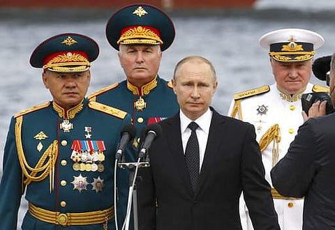 Russian President Vladimir Putin, center, Defence Minister Sergei Shoigu, left, Commander-in-Chief of the Russian Navy Vladimir Korolev, right, and Commander of Western military district Andrei Kartapolov arrive to attend the military parade during the Na