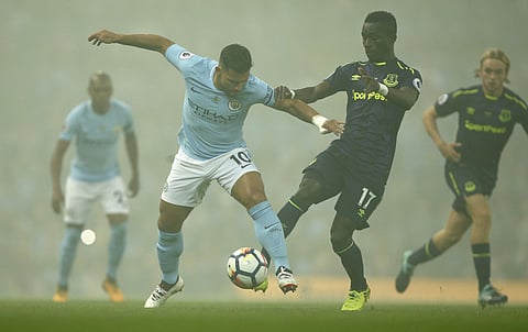 Shrouded in smoke from fireworks, Manchester City's Sergio Aguero and Everton's Idrissa Gueye in action during the English Premier League soccer match. | AP