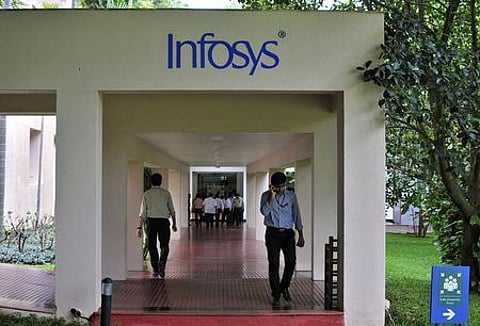 Employees walk along a corridor in the Infosys campus