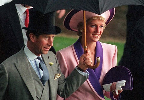 In this Wednesday, June 20, 1990 file photo, Britain's Princess Diana and Prince Charles, take shelter under an umbrella while attending the second day of the Royal Ascot horse race meet near London. | AP