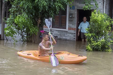 A man paddles a kayak along a flooded street caused by Typhoon Hato in Guangzhou in southern China (AP)