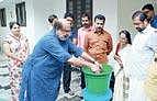 Finance Minister demonstrating the working of the kitchen bin to residents of Kunnukuzhy