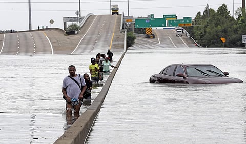 Evacuees wade down a flooded section of Interstate 610 as floodwaters from Tropical Storm Harvey rise Sunday, Aug. 27, 2017, in Houston.(AP)