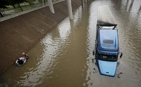 An unidentified man helps Carlos Torres, in tube, get to dry ground after Torres drove his tractor-trailer into a freeway flooded by Tropical Storm Harvey on Sunday, Aug. 27, 2017 | AP
