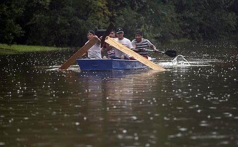 People use plywood to row a boat down Deats Road in Dickinson, Texas, Monday, Aug. 28, 2017, as floodwaters from Tropical Storm Harvey rise. (AP)